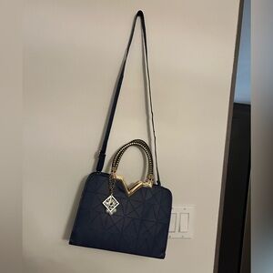 Medium, blue handbag with gold accents and a detachable shoulder strap.